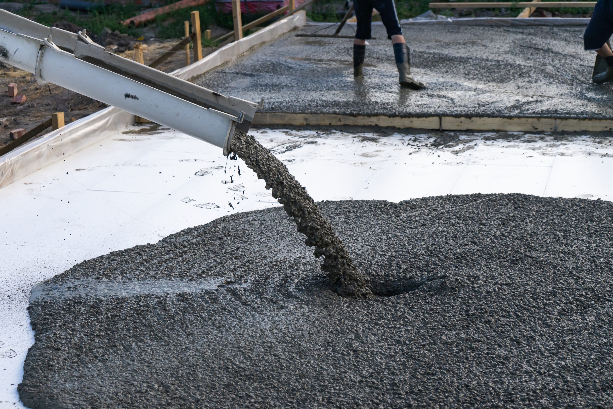 Fresh concrete being poured from a chute onto a slab